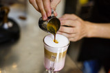 Barista is pouring coffee in milk - preparing coffe latte
