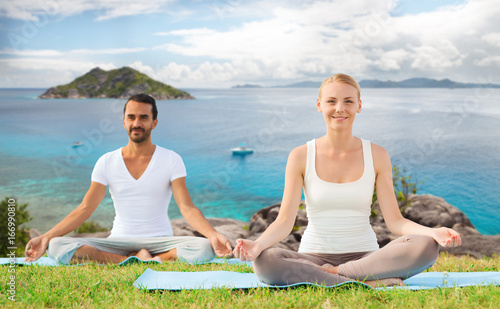 happy couple making yoga exercises outdoors