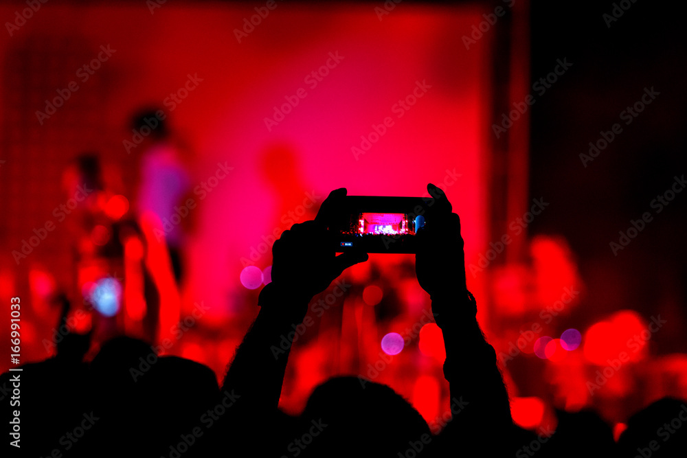 Hand with smartphone records live music festival, taking photo of concert stage live concert luxury party. Hand with smartphone records live music concert festival. Take photo in front of stage Hand with smartphone records live music festival, taking photo of concert stage live concert luxury party. Hand with smartphone records live music concert festival. Take photo in front of stage