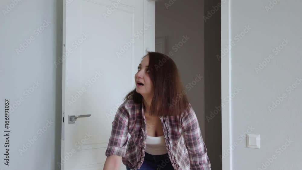 Happy Young woman moves into a new apartment with a box in his hands. Opens the door and looks around Happy Young woman moves into a new apartment with a box in his hands. Opens the door and looks around