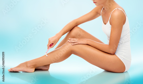 woman with safety razor shaving legs