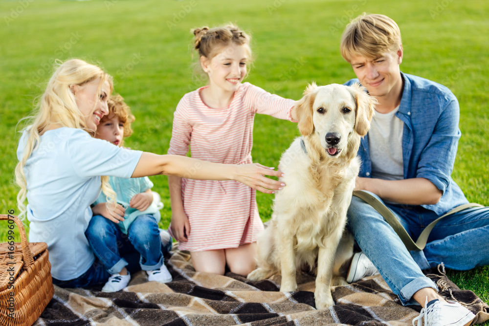 happy young family with dog resting on green meadow at picnic happy young family with dog resting on green meadow at picnic