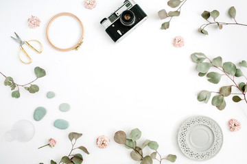 Flat lay border frame with retro camera, eucalyptus branches, plate and scissors on white background. Top view artist background with space for text.