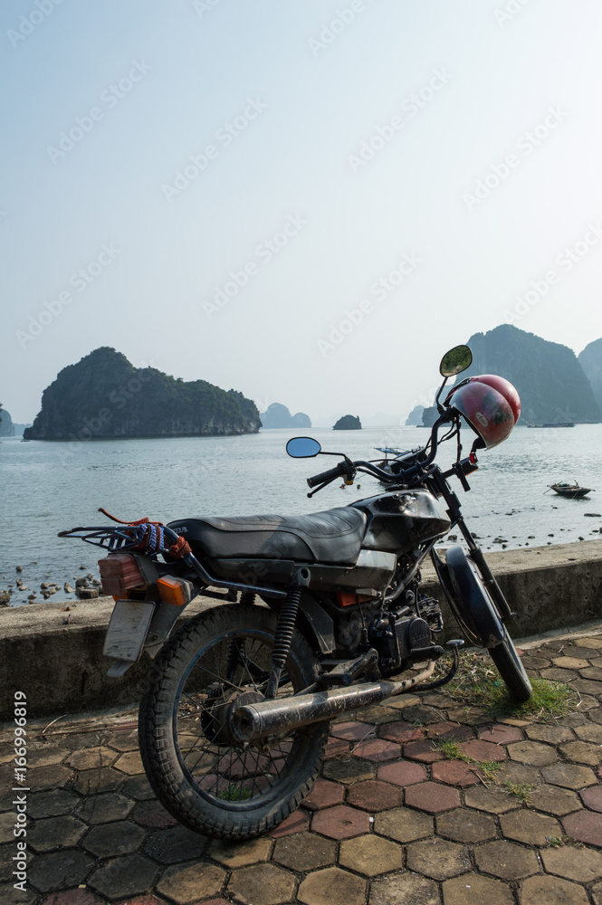 Motorcycle at Promenade and Limestone Formations and Boat in the Ocean at Ha Long Bay, Vietnam Motorcycle at Promenade and Limestone Formations and Boat in the Ocean at Ha Long Bay, Vietnam
