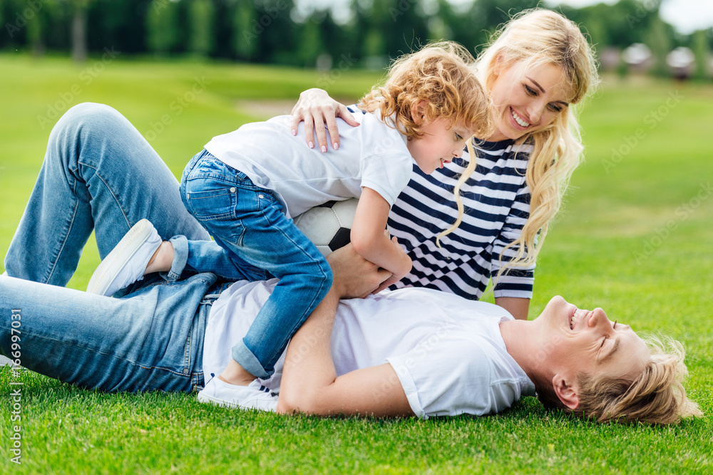 happy young parents with cute little son holding soccer ball and having fun at park happy young parents with cute little son holding soccer ball and having fun at park