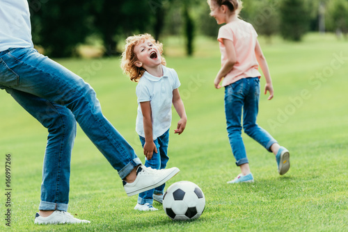 cropped shot of father with happy kids playing soccer in park