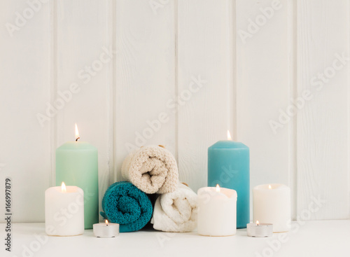 Spa composition. Spa candles. turquoise towels on rustic white wooden background.