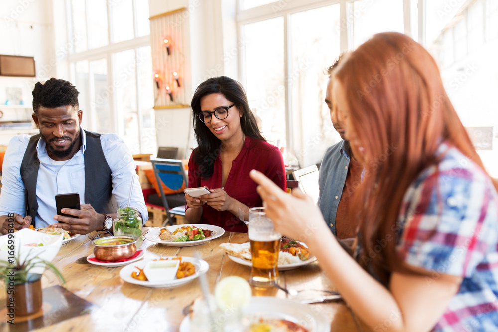 happy friends with smartphones at restaurant happy friends with smartphones at restaurant