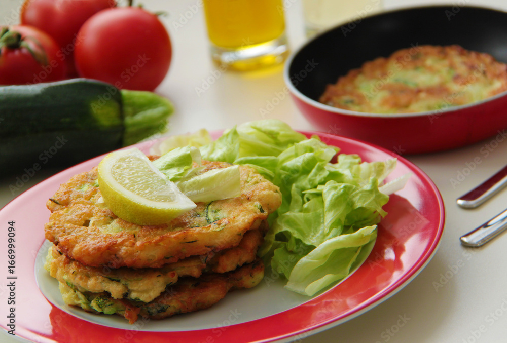 Vegetable zucchini pancakes served with fresh salad. Ingredients for cooking on background. Close up view. Vegetable zucchini pancakes served with fresh salad. Ingredients for cooking on background. Close up view.