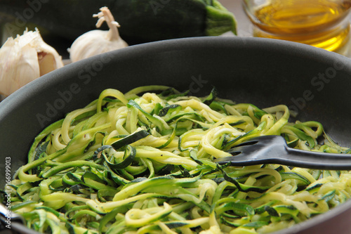 Vegetable zucchini spaghetti with olive oil and garlic. Ingredients for cooking on background. Close up view.