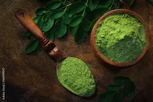 Overhead view of Moringa powder in an earthern pot on dark wooden background photo