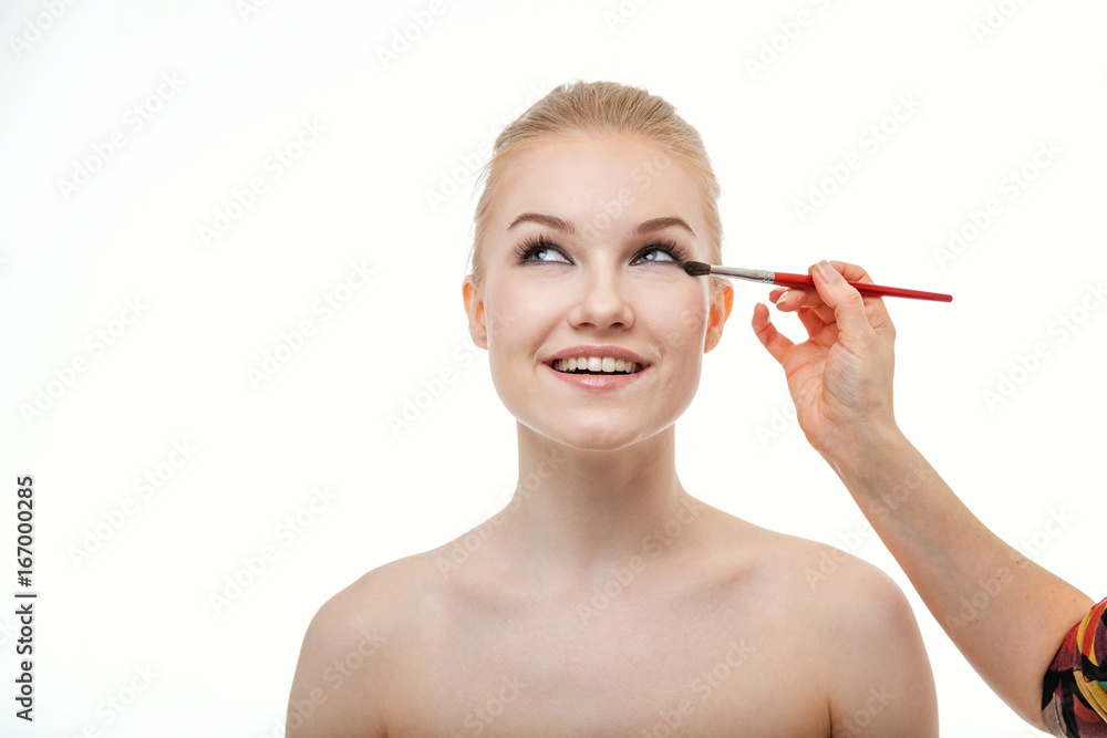 Makeup artist applying eye shadow for beautiful young woman on white background Makeup artist applying eye shadow for beautiful young woman on white background