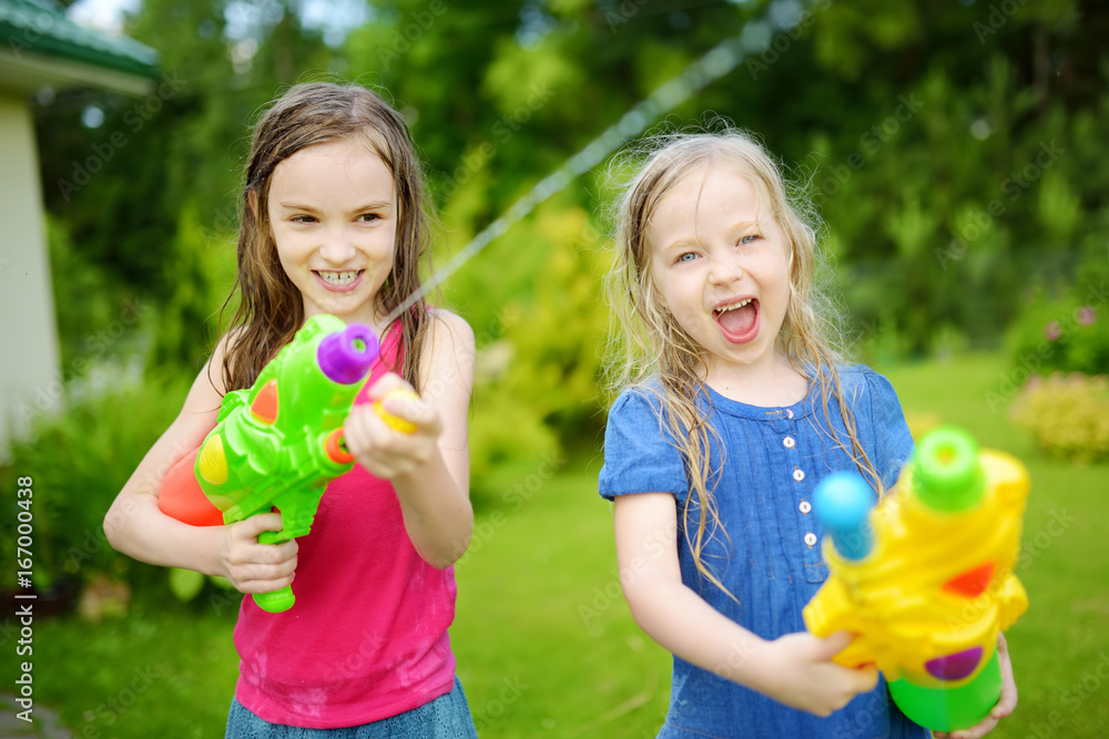 Adorable little girls playing with water guns on hot summer day. Cute ...