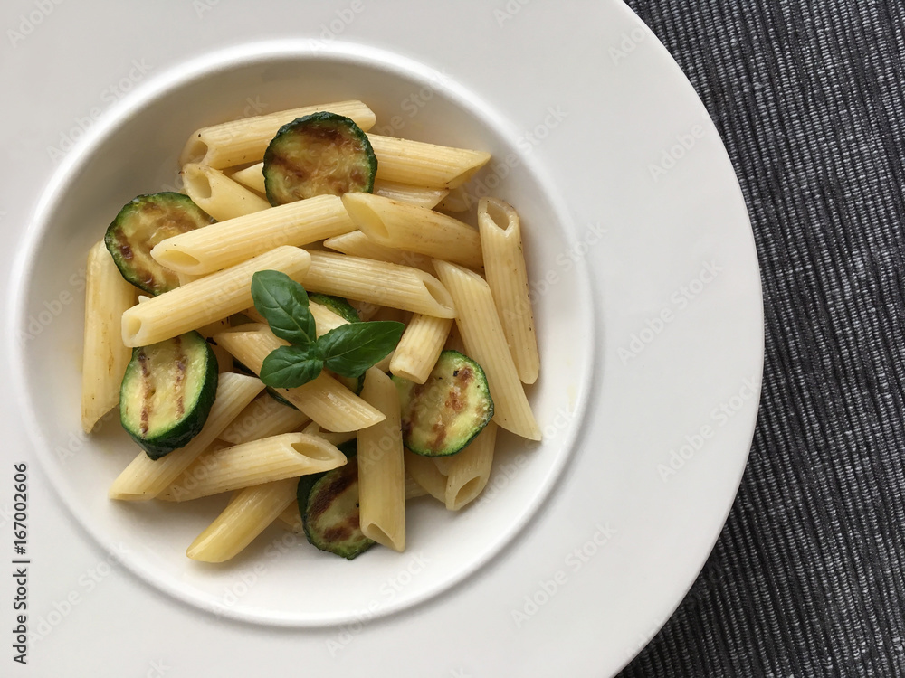 Pasta and grilled zucchini served on white plate. Top view. Pasta and grilled zucchini served on white plate. Top view.