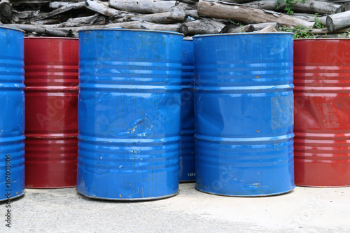 Empty tank of 200 liter fuel. blue and red color Put in front of old wood pile.