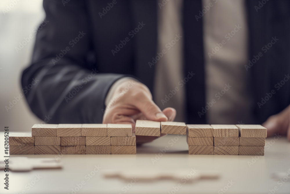 Close up of fingers from hand of business man assembling a bridge Close up of fingers from hand of business man assembling a bridge