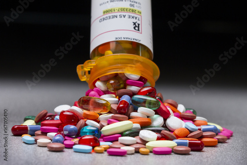 A prescription pill bottle spilling out an assortment of pills photo