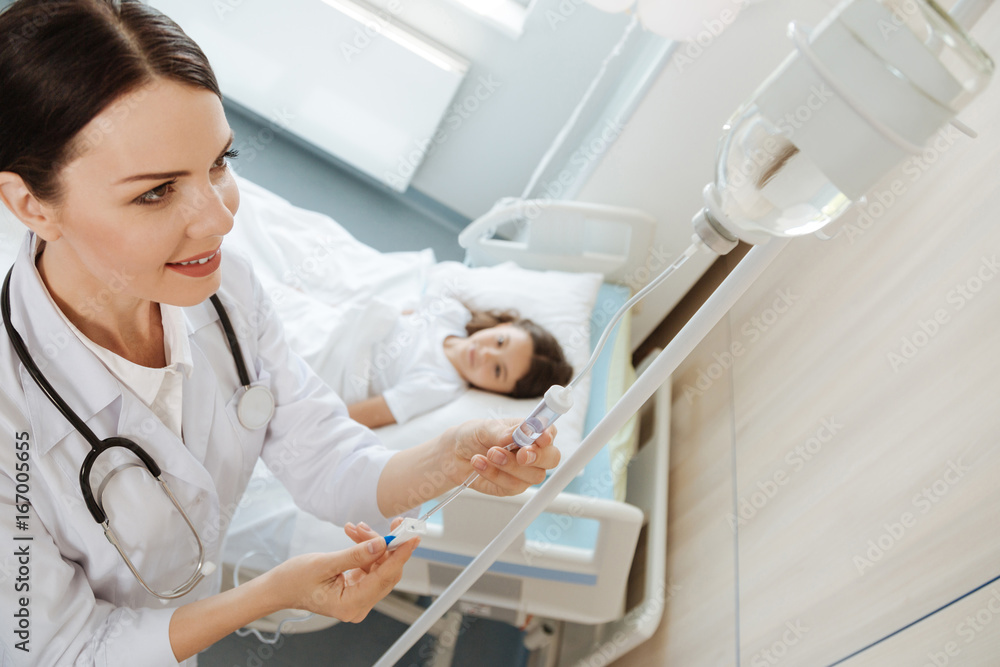 Positive delighted doctor looking at the IV bottle Positive delighted doctor looking at the IV bottle