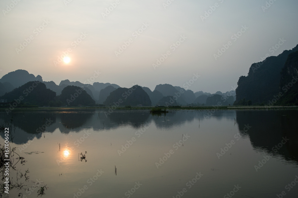 Naklejka premium Limestone Landscape with Lake, Sunset and Reflection, Tam Coc, Vietnam