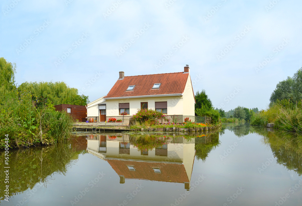 Obraz premium Une jolie maison se reflétant dans les eaux calmes des marais de Saint Omer