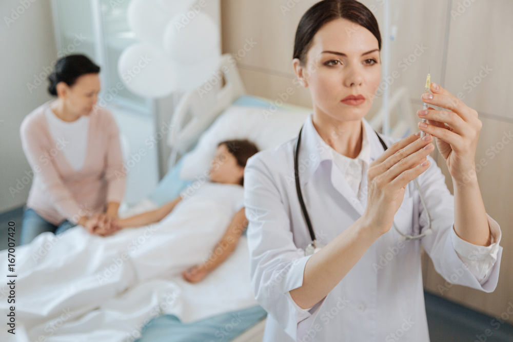 Fototapeta premium Serious skillful doctor preparing a syringe