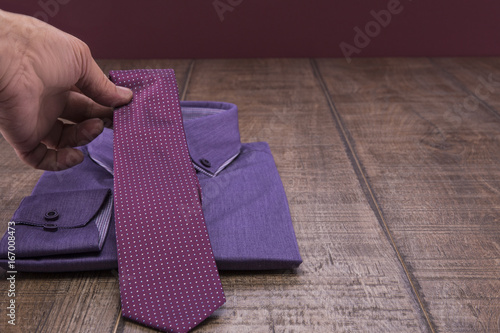 Lilac man's shirt and lilac ties on a wooden table. Background burgundy. photo