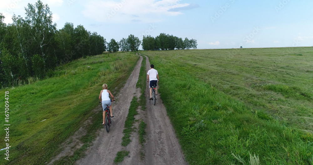 a young man with a child riding bicycles on a country road. Shooting from a drone. Sports outdoors