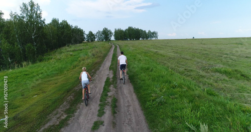 a young man with a child riding bicycles on a country road. Shooting from a drone. Sports outdoors