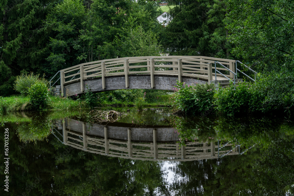 Über Wasser führende Holzbrücke mit Spiegelung