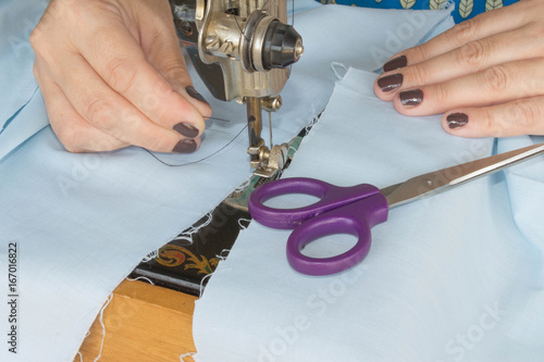 closeup of woman hands sewing yellow cloth outdoors photo