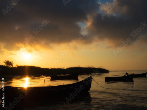 beautiful sunset over water and silhouette fishing boat © Constantin