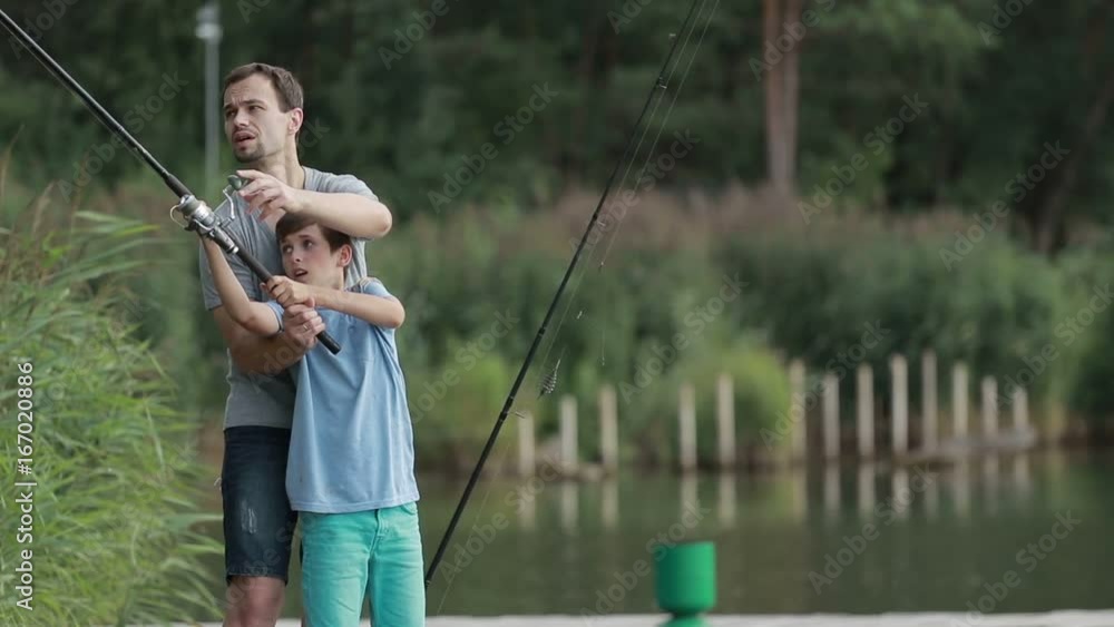 Teenage boy learning to fish with father's help Teenage boy learning to fish with father's help