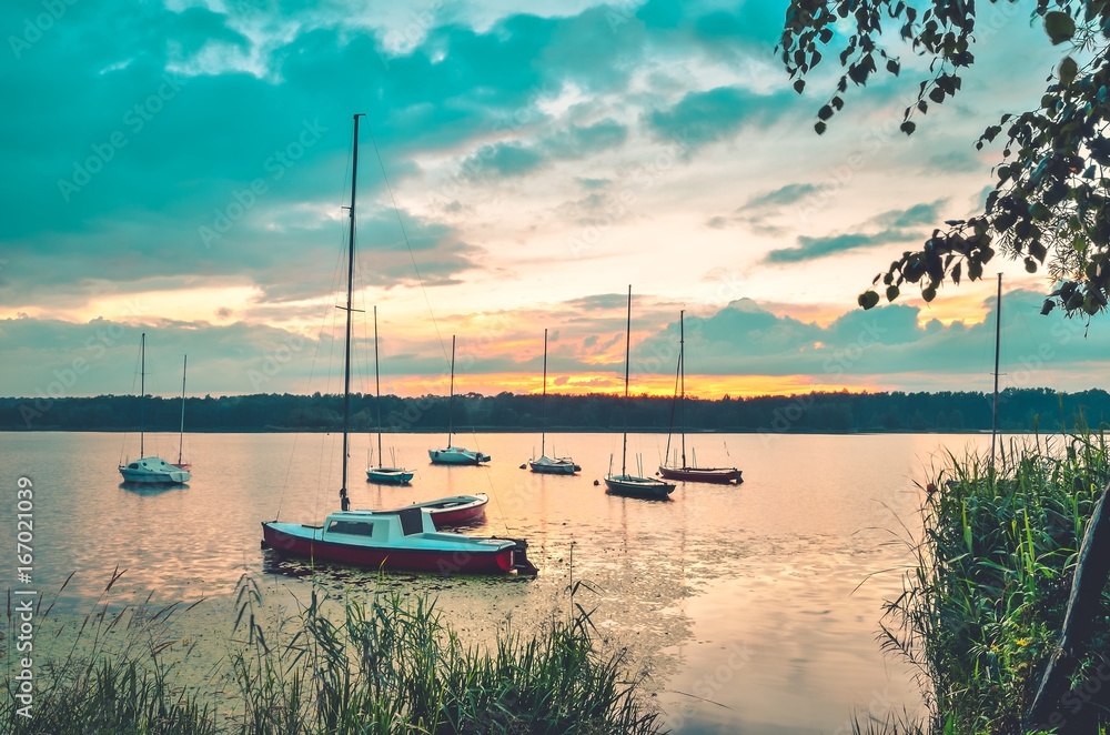 Summer evening landscape. Boats on the lake and colorful sky.