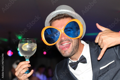 Canvas Print Fun looking man at a party holding a cocktail and sticking his tongue out