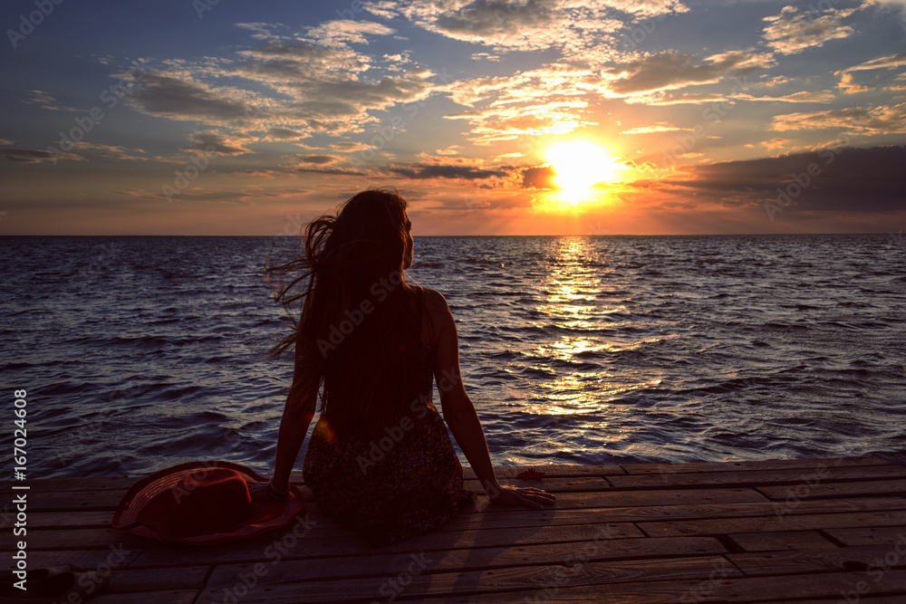 The girl at the seaside resting, meditating, relaxing and admiring the sunset