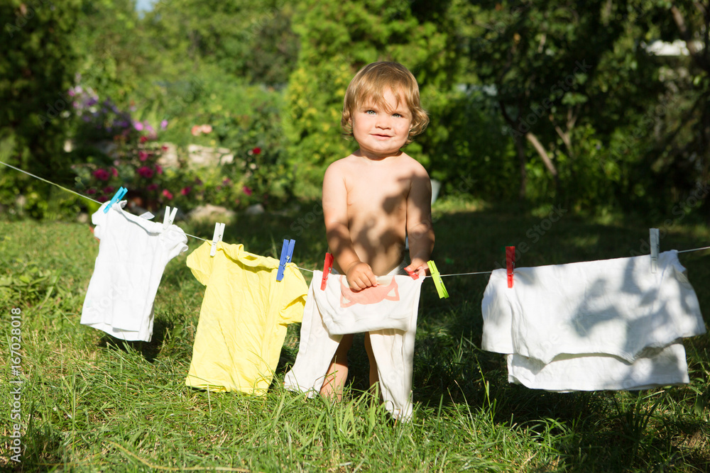 Fototapeta premium fun happy baby girl to wash clothes and laughs in the meadow on a sunny summer day.
