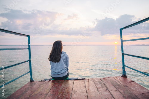 фотографія woman sitting alone on the pier and enjoing the view