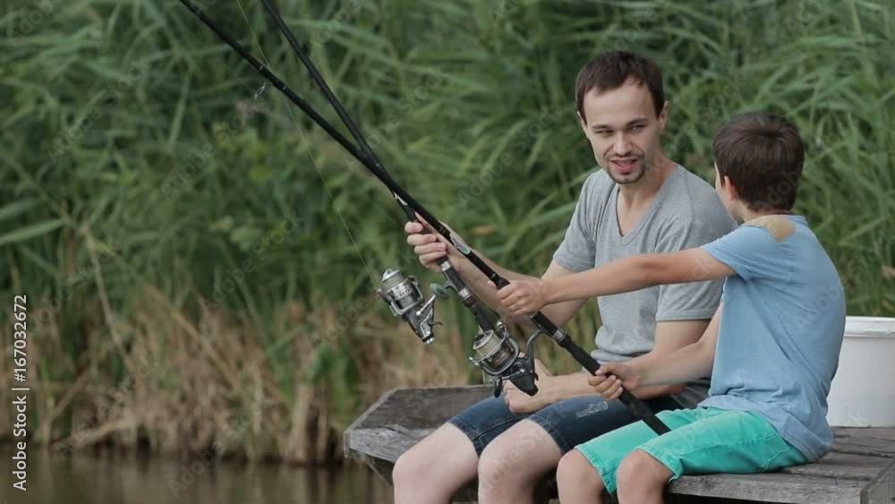 Positive father and son fishing together on pond Positive father and son fishing together on pond