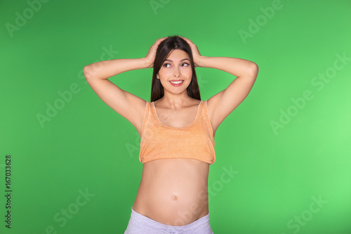 Young pregnant woman choosing name for baby on green background