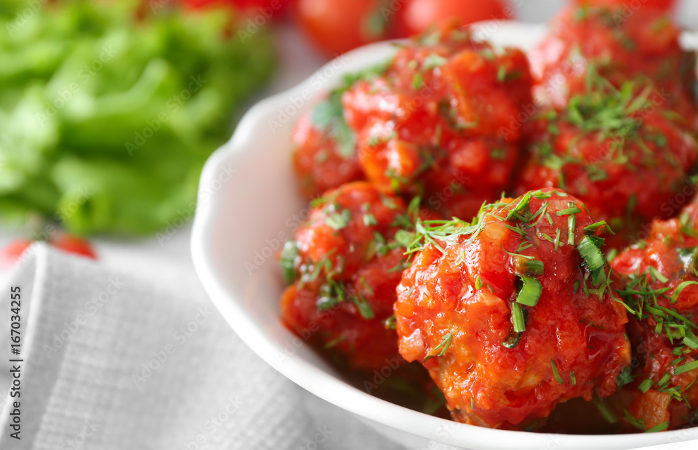 Bowl with delicious turkey meatballs and tomato sauce on table, closeup