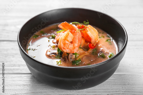 Delicious soup with shrimps in bowl on wooden table