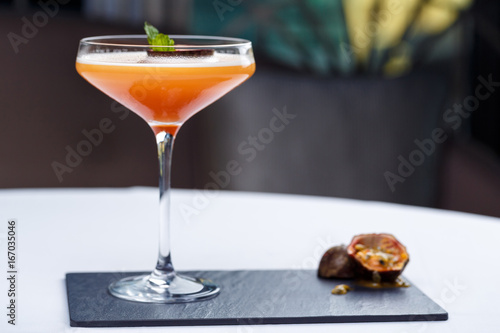 Cold cocktail with passion fruit on stone background.