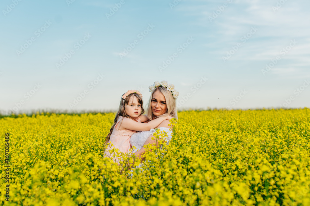 Mom and child having fun in a yellow flowering field Mom and child having fun in a yellow flowering field