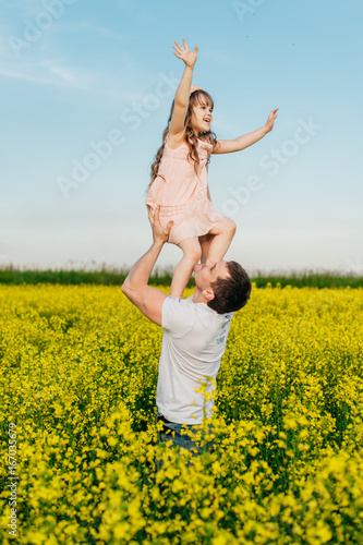 Man with child in a yellow field at sunset