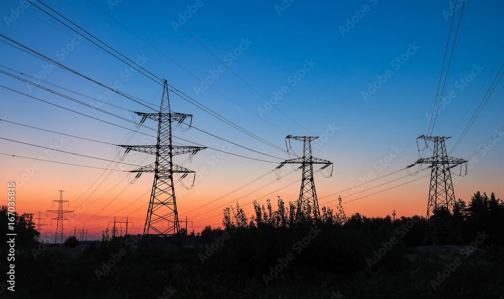 Fototapeta premium High-voltage power lines during fiery sunrise