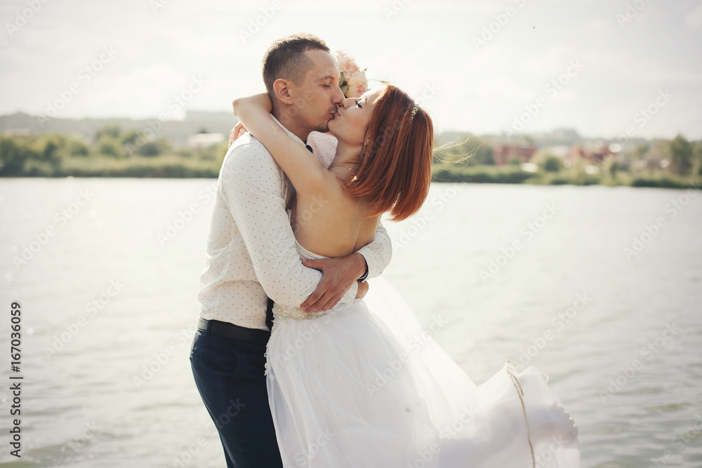 Elegant gentle stylish groom and bride near river or lake. Wedding couple in love Elegant gentle stylish groom and bride near river or lake. Wedding couple in love
