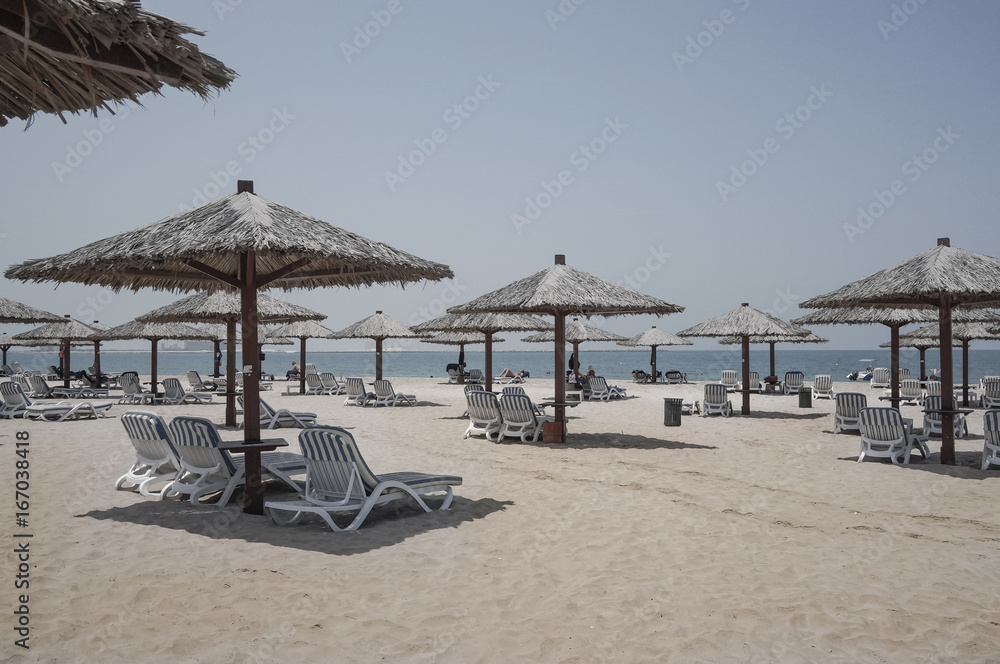 Dubai. Heavenly oasis in Ras al Khaimah. The beach with sunbeds and sunshades in Dubai, on the shores of the Arabian Gulf. Toning.
