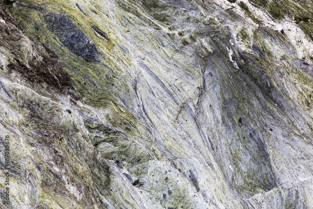 An abstract close up of mineral veins running through green rock in a textured background. An abstract close up of mineral veins running through green rock in a textured background.