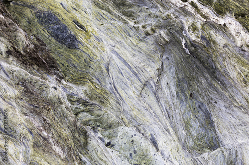 An abstract close up of mineral veins running through green rock in a textured background.