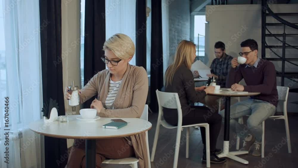 Young beautiful woman sitting at the table and drinking coffee indoor Young beautiful woman sitting at the table and drinking coffee indoor